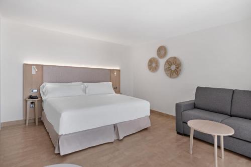 a bedroom with a bed and a couch at Occidental Cala Viñas in Cala Vinyes