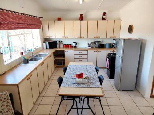 uma cozinha com uma mesa e um frigorífico em Sunnyside Farm Cottage, Oudtshoorn, South Africa em Oudtshoorn