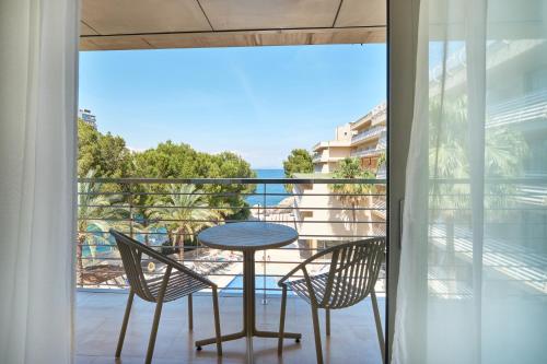 a balcony with a table and chairs and a view of the ocean at Occidental Cala Viñas in Cala Vinyes