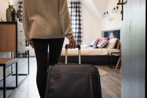 a woman is pulling a suitcase in a living room at Hotel Do Poduchy in Zawiercie