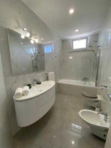 a white bathroom with a tub and a sink and a bath tub at Melitta apartment Giardini Naxos in Giardini Naxos