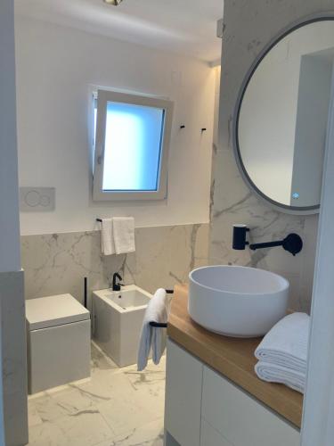 a white bathroom with a sink and a mirror at “CapriOleum” esclusive place in Anacapri