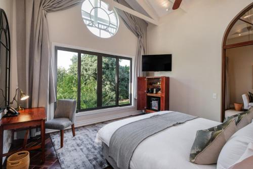 a bedroom with a bed and a desk and a window at Palm River Hotel in Victoria Falls