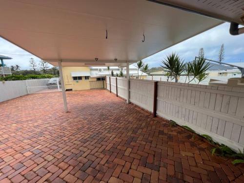 a brick patio in front of a house with a white fence at The Cove Cottage in Pemberton
