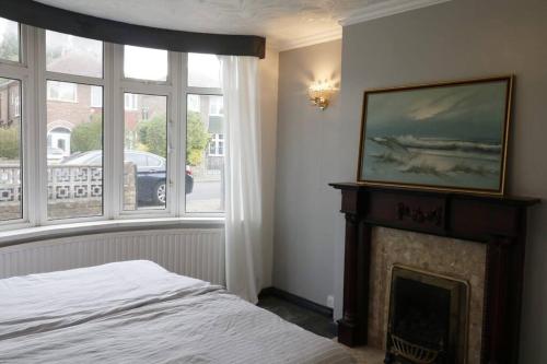 a bedroom with a bed and a fireplace with windows at A stylish four bedroom house in wollaton in Nottingham