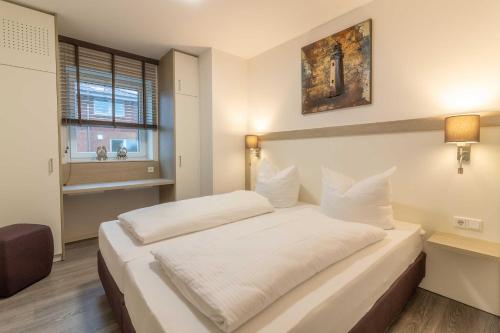 1 dormitorio con 1 cama con sábanas blancas y ventana en Fewo Störtebeker Haus Kachelotplate, en Hooksiel
