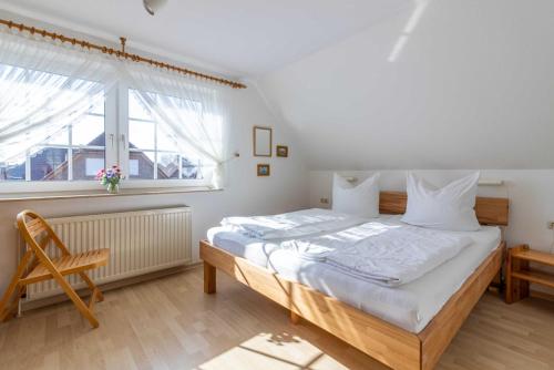 - une chambre avec un grand lit et une fenêtre dans l'établissement Haus Suedwind, à Hooksiel