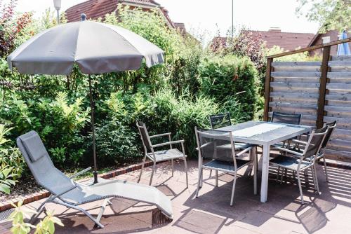 un patio con mesa, sillas y sombrilla en Haus am Teich, en Hooksiel