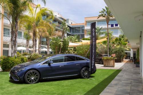 a blue car parked on the grass in front of a building at Altafulla Mar Hotel in Altafulla