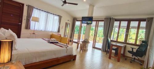 a bedroom with a bed and a desk and windows at Le Grand Bleu Hotel in Wok Tum