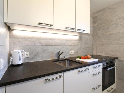 a kitchen with white cabinets and a sink at Hotel St Hubertus in Egg