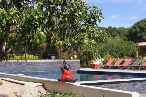 a woman sitting on a bench next to a swimming pool at Les Jardins De Santa Giulia - Charmante chambre dhte 1 in Porto-Vecchio
