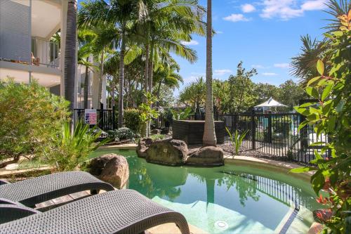 una piscina en un complejo con 2 bancos y palmeras en Salt&Pepper Sanctuary - Plunge Pool Resort Apartment by uHoliday - 2BR, 1BR and Studio Hotel Room configurations available en Kingscliff