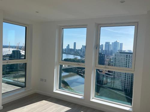 a room with three windows with a view of the city at Luxury penthouse with stunning views near Canary Wharf in London