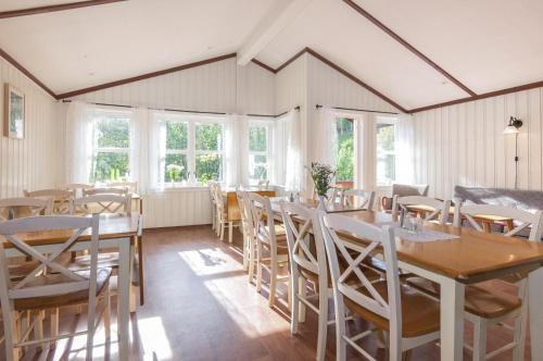 a dining room with tables and chairs and windows at Malmplassen Gjestegård Bed & Breakfast in Tolga