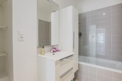 La salle de bains blanche est pourvue d'un lavabo et d'une douche. dans l'établissement La Halte de Saint-Pierre, à Clermont-Ferrand
