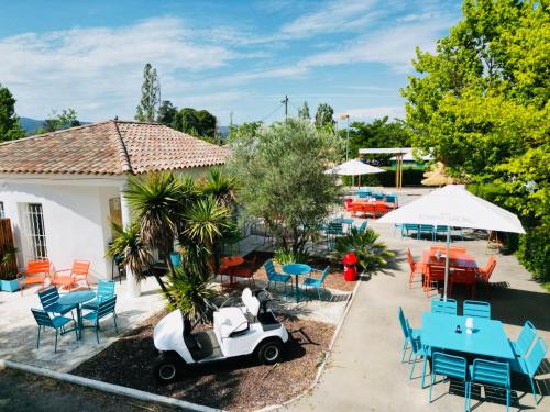 un patio al aire libre con mesas, sillas y una moto en Camping Paradis Family les Rives de l'Hérault, en Gignac
