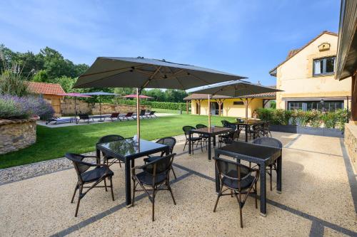 a group of tables and chairs with an umbrella at Domaine du Bugassou, Chambres, Table d'hôtes & SPA in Belvès