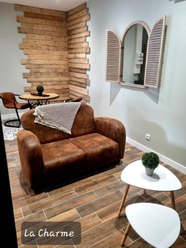 - un canapé en cuir brun dans un salon avec des tables dans l'établissement Gite La Charme avec spa, 