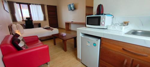 a kitchen with a microwave and a red chair in a room at Le Grand Bleu Hotel in Wok Tum