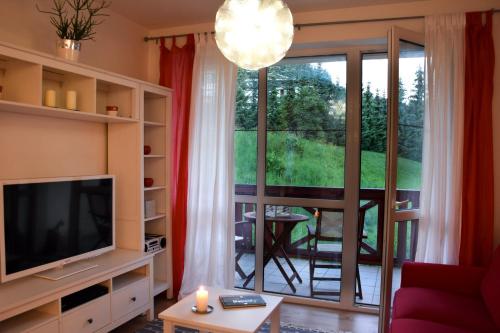 a living room with a television and a balcony at Štýlový apartmán v srdci Donovalov in Donovaly