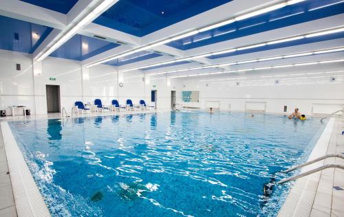 une grande piscine intérieure avec des plafonds bleus dans l'établissement SPA-Hotel SINDICA, à Nalchik