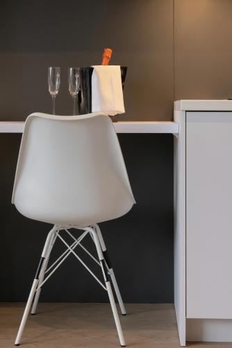 a white chair sitting in front of a desk with wine glasses at Młyńska 10 by Apartamenty Nad Parsętą in Kołobrzeg