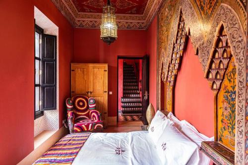 a bedroom with red walls and a bed and a chair at Palais El Roucar in Marrakesh
