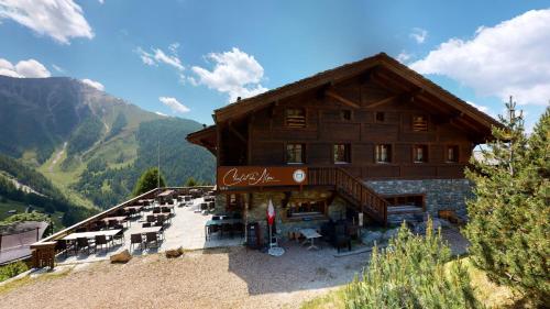 a large wooden building with chairs in front of it at Chalet des Alpes NATURE & MOUNTAIN by Alpvision Résidences in Prarion