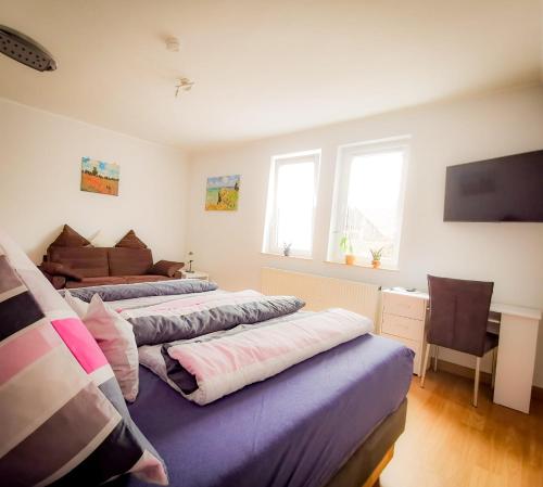 2 łóżka w pokoju z biurkiem i telewizorem w obiekcie Ferienwohnung Maris w mieście Burghaun