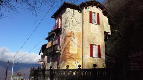 a tall building with red windows and a fence at B&B Il Balcone sul Lago in Brunate