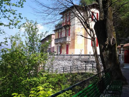 a building on a hill with a tree and a fence at B&B Il Balcone sul Lago in Brunate