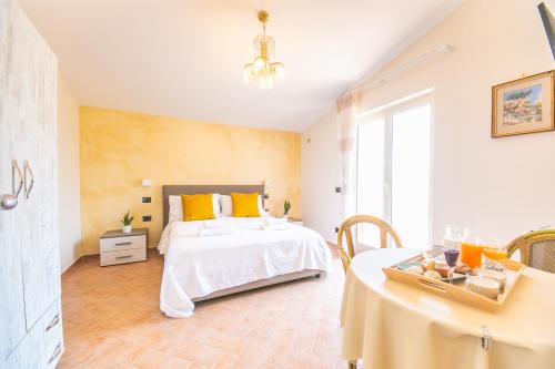 Un dormitorio con una cama con almohadas amarillas y una mesa. en Perla Beach Stabia B&B, en Castellammare di Stabia
