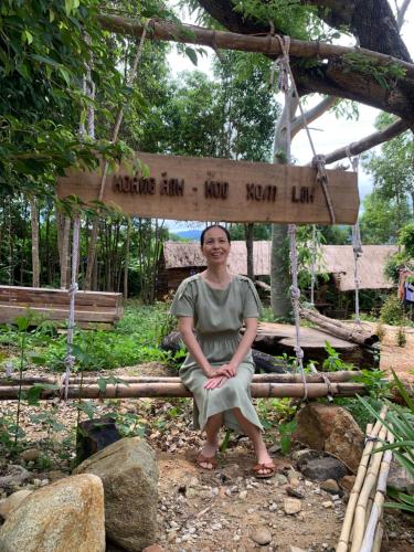 a woman sitting on a swing in front of a sign at Khu Du Lịch Sinh Thái, Nghỉ dưỡng Homestay Hoàng Ánh - Kon Xom Luh in Kon Tum