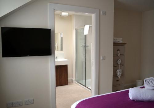 a bedroom with a tv on a wall and a bathroom at Inverfinn in Killin