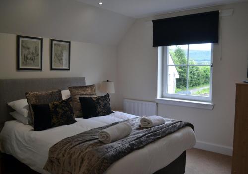 um quarto com uma cama com almofadas e uma janela em Gleann Fia House em Killin
