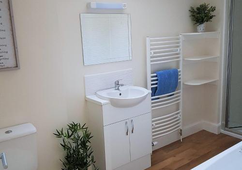 een witte badkamer met een wastafel en een spiegel bij Álainn Eve in Killin