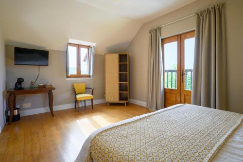 a bedroom with a bed and a desk and window at Domaine du Bugassou, Chambres, Table d'hôtes & SPA in Belvès
