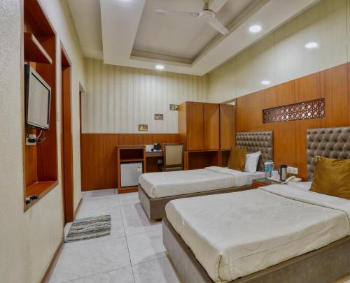 a hotel room with two beds and a television at Hotel President, Pure Veg in Indore