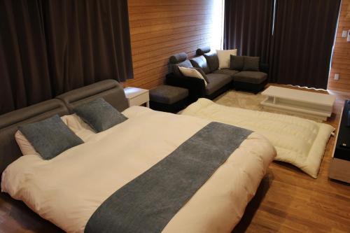 a bedroom with a large bed and a couch at 佐世保VILLA青鹿Ur1 in Sasebo