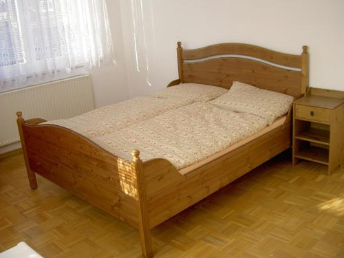 トレボンにあるPenzion Chocholoušekのナイトスタンド付きの部屋の木製ベッド1台