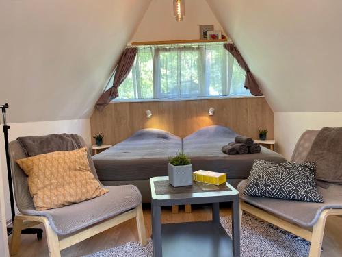 a bedroom with a bed and two chairs and a table at Camping Milk in Usmenieki