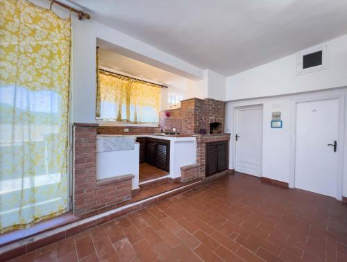 an empty kitchen with a brick wall and a window at Azienda Agricola Sapereta in Porto Azzurro