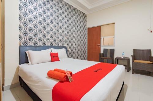 a bedroom with a large bed with a red blanket at RedDoorz near Pasar Klandasan Balikpapan in Balikpapan