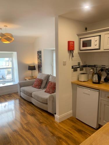 een woonkamer met een bank en een keuken bij Errismore House in Clifden