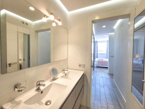 a white bathroom with a sink and a mirror at Ocean Garden Suite El Sol in Adeje