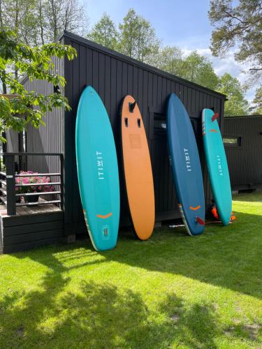 four surfboards are lined up against a wall at Camping Milk in Usmenieki