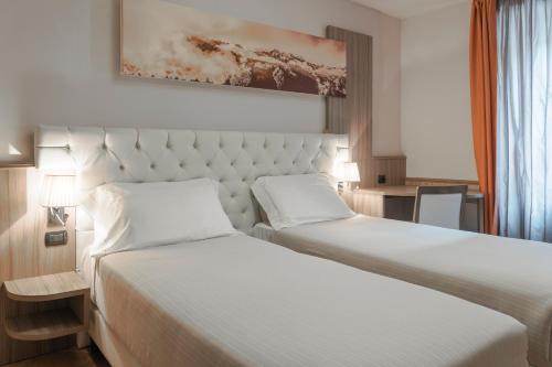 pokój hotelowy z dwoma łóżkami z białymi prześcieradłami w obiekcie Hotel Garnì Cristallo w mieście Ponte di Legno