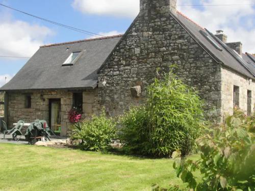 a stone house with a grass yard in front of it at Vacances au calme in Plounevez-Moëdec