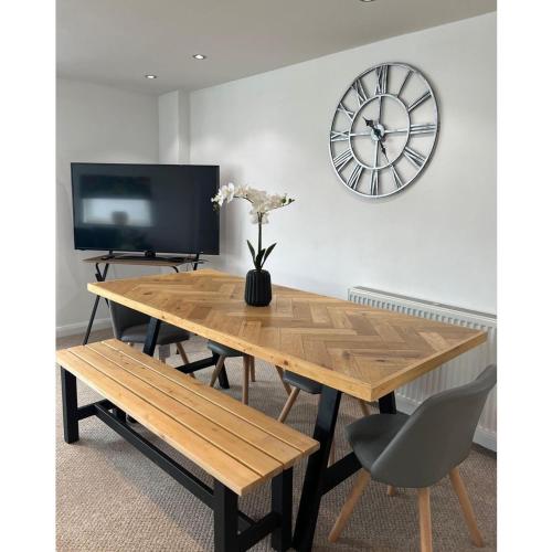 a wooden table with a bench and a clock on a wall at The Hideout (Garden Flat, 4 Dragon Road) in Harrogate